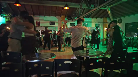 Social de baile con luces verdes y mesas alrededor de la pista